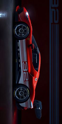 a red sports car hanging from the side of a wall in front of a black background