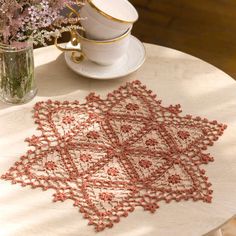 a table topped with a cup and saucer covered in crocheted doily