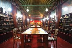 a long wooden table sitting in the middle of a room filled with bookshelves