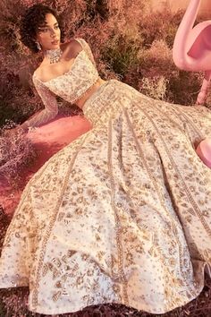 a woman in a white dress sitting on the ground next to a pink flamingo