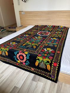 a bed with a black and multicolored quilt on it's headboard