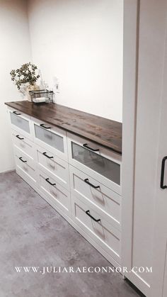 an empty room with white drawers and wooden counter top on the wall next to a door