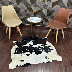 two chairs and a table with a cow hide rug on the floor in front of it