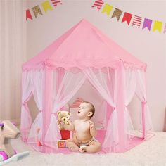 a baby is sitting in a pink play tent