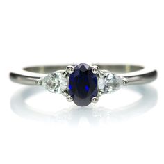 a three stone ring with an oval blue sapphire surrounded by smaller white diamonds on the band