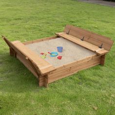 a wooden sandbox in the middle of some grass