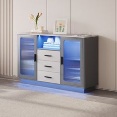 a white and grey cabinet with blue lights on it's sides, next to a window