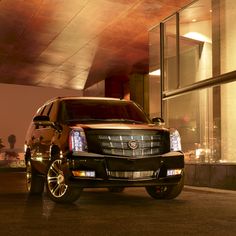 a red cadillac truck parked in front of a building at night with people walking by