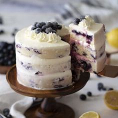 a white cake with blueberries and lemons on it is cut in half to show the layers