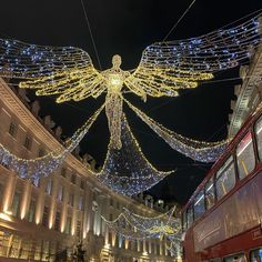 a double decker bus driving down a street with christmas lights hanging from it's sides