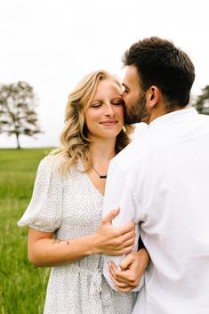 a man and woman are standing in the grass with their eyes close to each other