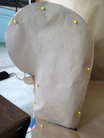 the back of a chair that is covered in paper and some yellow pins on it