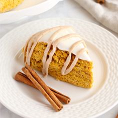 a piece of cake sitting on top of a white plate next to some cinnamon sticks