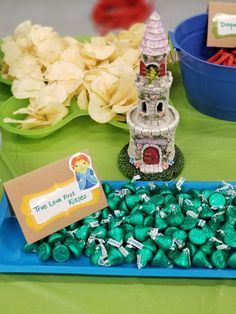 a table topped with lots of candy next to a blue tray filled with candies