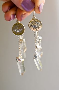 The cutest crystal drop earrings a girl could want! These Quartz earrings dangle sweetly from the evil eye protector symbol, both protecting your peace and enhancing your third eye. To see clearly is to know your path and your self. Wear these layered with our matching Quartz Drop Lariat Necklace and our Heart Work Green Fedora as seen in photos! Quartz crystal pendants with silver detailing hanging from a silver evil eye pendant Drop length approximately 2 5/8" Weight: .25 oz Handmade in Arizon Protector Symbol, Protecting Your Peace, Crystal Pendants, Quartz Crystal Pendant, Crystal Suncatchers, Crystal Accessories, Eye Pendant, Evil Eye Pendant, Crystal Drop Earrings