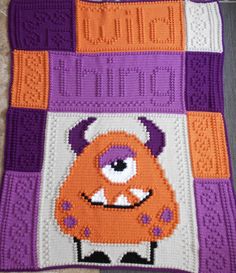 a crocheted blanket with an orange and purple monster design on it's side