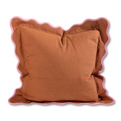 a brown pillow with pink piping on the front and back side, sitting against a white background