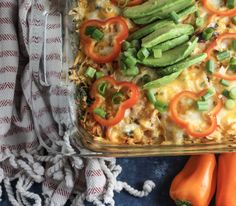 a casserole dish with tomatoes, green peppers and avocado on top