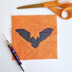 an orange piece of paper with a bat cut out on it next to some scissors