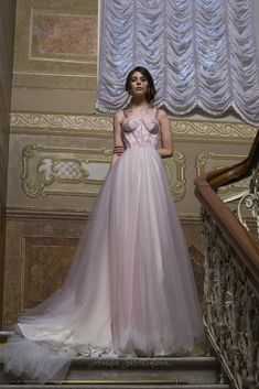 a woman in a pink dress standing on some stairs