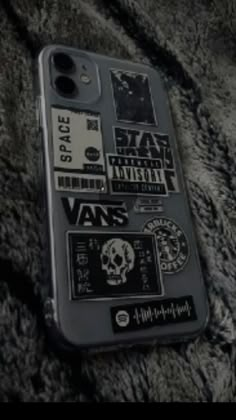 a cell phone with stickers on it laying on a fur covered surface in black and white