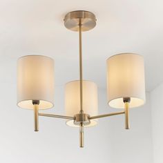 three light chandelier with white shades hanging from the ceiling