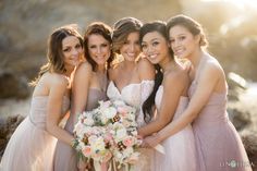 four bridesmaids pose for a photo in front of the ocean