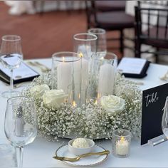 a centerpiece with candles and flowers on a white table cloth at a wedding reception