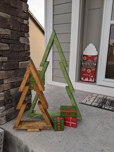 a wooden christmas tree sitting on top of a porch next to blocks of red and green wood