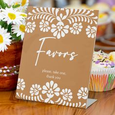 there is a card that says favors on it next to cupcakes and flowers