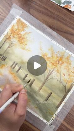 someone is painting an autumn scene with watercolors