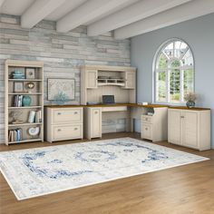 a room with a rug, desk and bookcases in the middle of it