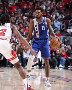 two basketball players in action on the court with fans watching from the stands behind them