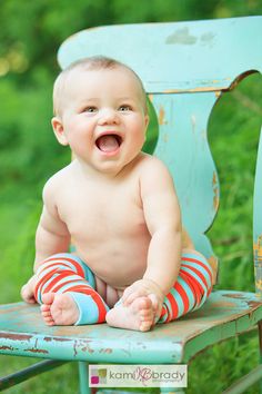 a baby sitting on top of a blue chair with his legs crossed and mouth wide open