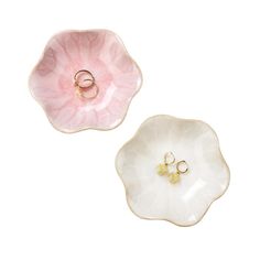 two pink and white flower shaped dishes with gold rings on the bottom one has a ring holder in the middle