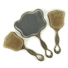 This intricate USA made mirror and brush set consists of a hand mirror, with beveled glass, and gilded carved handle making it pretty heavy. The mirror is in wonderful condition without clouds.  The 2 hair brushes are made of wood and nylon bristles. The handles are gilded gold and the backs are also glass. The ladies brush has a small hand painted cameo design which is signed.  Measurements are of the mirror Victorian Hand Mirror, Victorian Hand, Mirror 3, Hair Brushes, Hand Mirror, Vanity Table, Gold Gilding, Beveled Glass, Small Hands