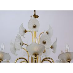 a chandelier with white flowers hanging from it's center and four lights on each side