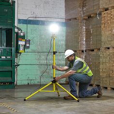 a man kneeling down next to a yellow tripod with a light on top of it