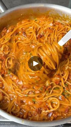 a pot filled with pasta and sauce being stirred by a ladle on the stove