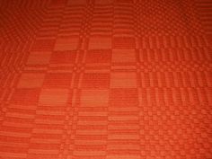 an orange and black checkered pattern on a bed sheet that has been made into a quilt