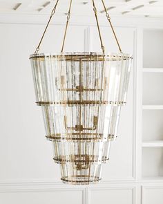 a chandelier hanging from the ceiling in a room with white walls and shelves