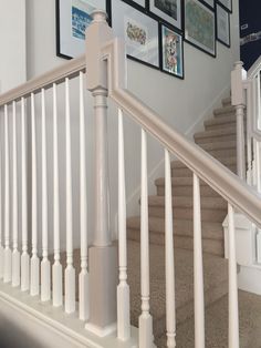 a staircase with white railing and pictures on the wall