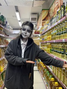 a person with painted face and makeup in a store aisle holding out their hand to the camera