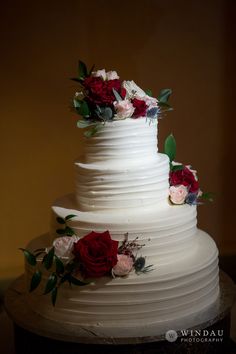 a white wedding cake with red and pink flowers