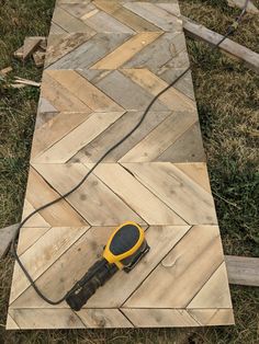 a yellow and black device on top of wooden planks in the grass with power cord attached to it