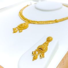 This 22k gold necklace set features a gorgeous design adorned with delicate leaf motifs, embodying natural elegance and luxury. Weighing 35.0 grams, the set is crafted from radiant yellow gold with a 16-inch necklace, adjustable by 1.75-inch links, and secured with a hook lock. The matching 1.75-inch earrings, complete with screw-back posts, enhance the set’s cohesive beauty. The leaf-adorned drop design adds a graceful touch, making this set perfect for those who appreciate timeless, nature-ins