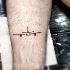 a small airplane tattoo on the left inner forearm and foot, as well as an arrow