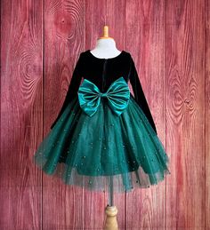 Little Darln Boutique  Our enchanting Knee Length flower girl dresses are sure to turn heads! This beautiful elegant sophisticated dress is handmade, the bodice consists of soft black velvet material, the back of the dress consists of a hunter green satin detachable bow, with zipper for closure. The skirt consists of 4 Hunter Green layers of tulle with the top layer consisting with sowed in pearl beads. The fifth layer is made of lining with crinoline for fullness.  Dress Is Pictured with a petticoat NOT INCLUDED https://www.etsy.com/listing/1316417982/white-knee-length-petticoat-wedding?click_key=41cb8b0ae4587efa582b0a433f3f5e0cde12aec0%3A1316417982&click_sum=af1df37b&ref=shop_home_active_1 Visit our store, more items to come!  https://www.etsy.com/shop/LittledarlnBoutique?ref=profile_hea Hunter Green Flower Girl Dress, Elegant Tulle Holiday Dress For Festive Occasions, Holiday Princess Dress With Bow, Fitted Tutu Dress For Christmas Fancy Dress, Fitted Christmas Tutu Dress For Fancy Dress, Green Christmas Princess Dress For Dress-up, Christmas Princess Dress With Bow, Elegant Festive Tulle Princess Dress, Christmas Wedding Princess Dress With Bow