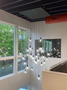 a room that has some lights hanging from the ceiling in front of it and windows