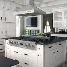 a kitchen with white cabinets and black counter tops is pictured in this image, there are two green apples on the stove top